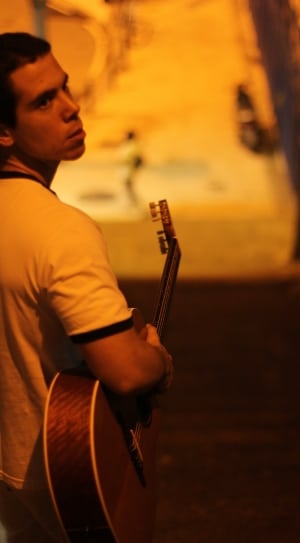 man in white shirt carrying acoustic guitar thumbnail