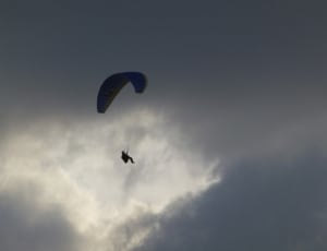 person parachute under gray and white sky thumbnail