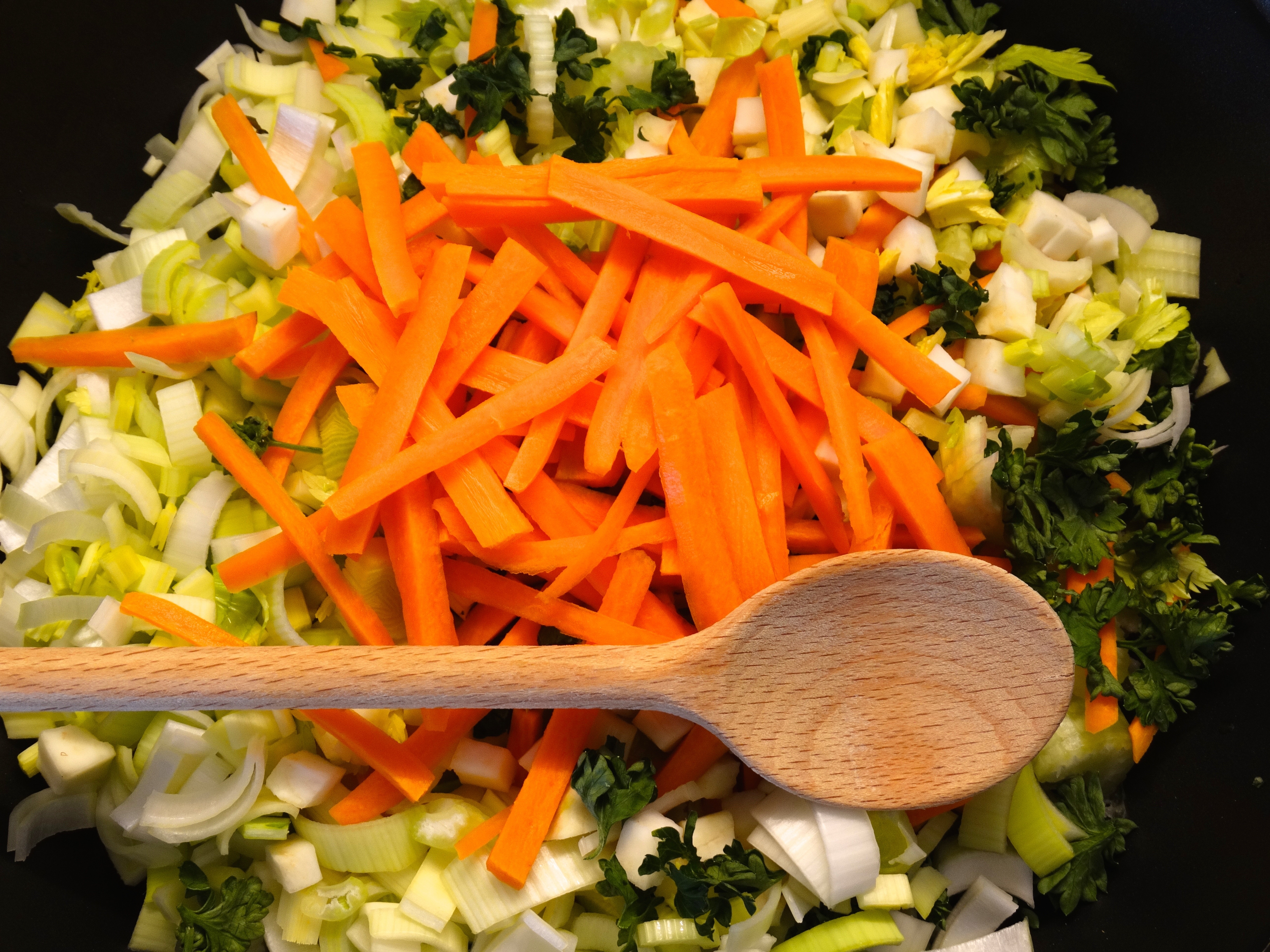 slice carrots and green vegetable with brown spoon