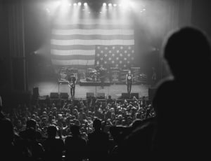photo of live concert with united states of america flag gray scale photography thumbnail