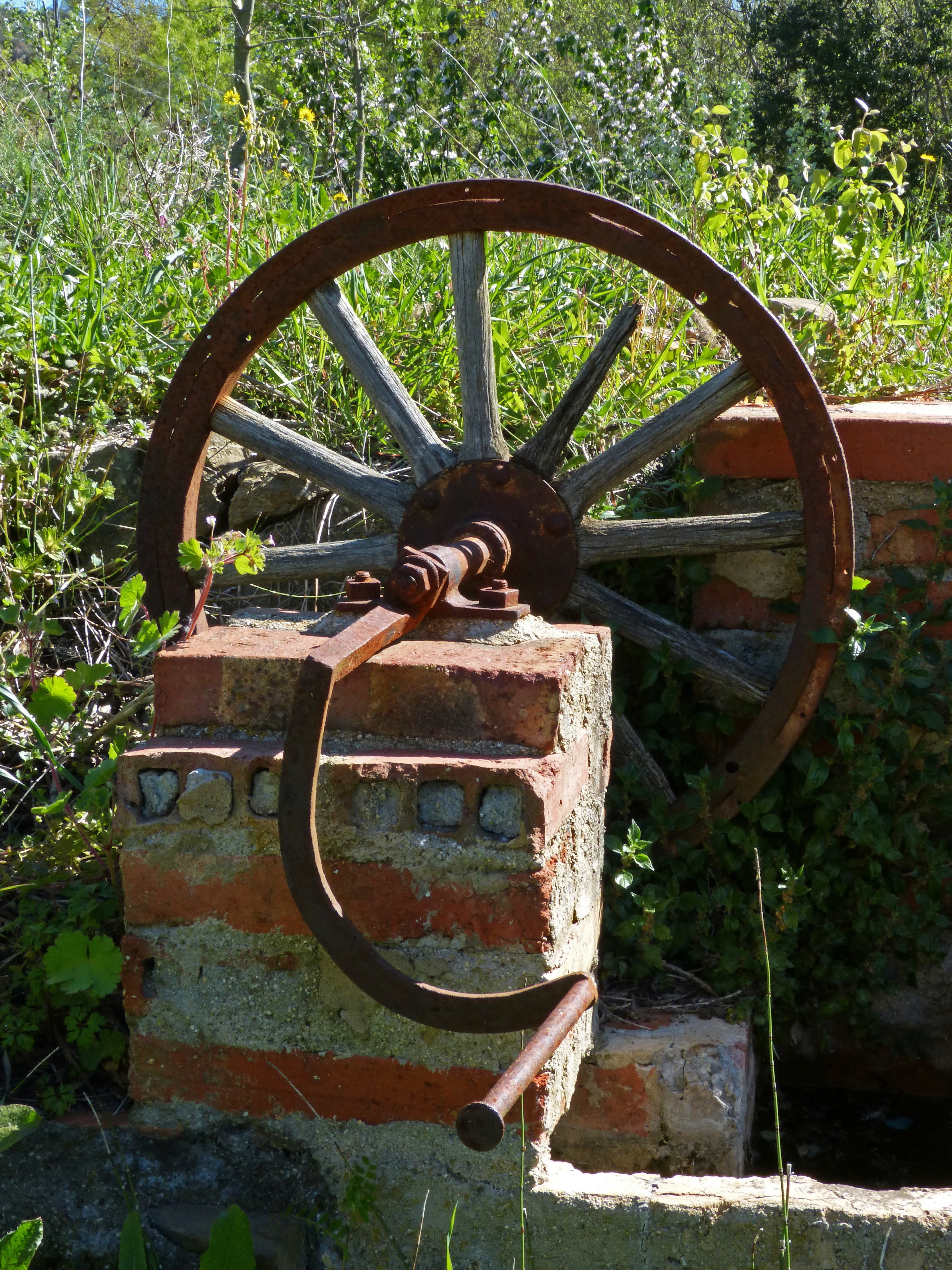 brown metal wheel near gray concrete bricks
