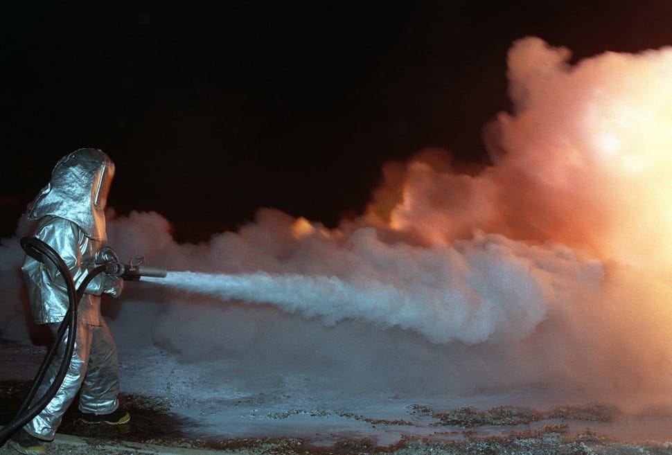 fireman in silver uniform holding spray hose preview