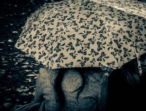 grayscale photo of person using umbrella with ribbon decors thumbnail