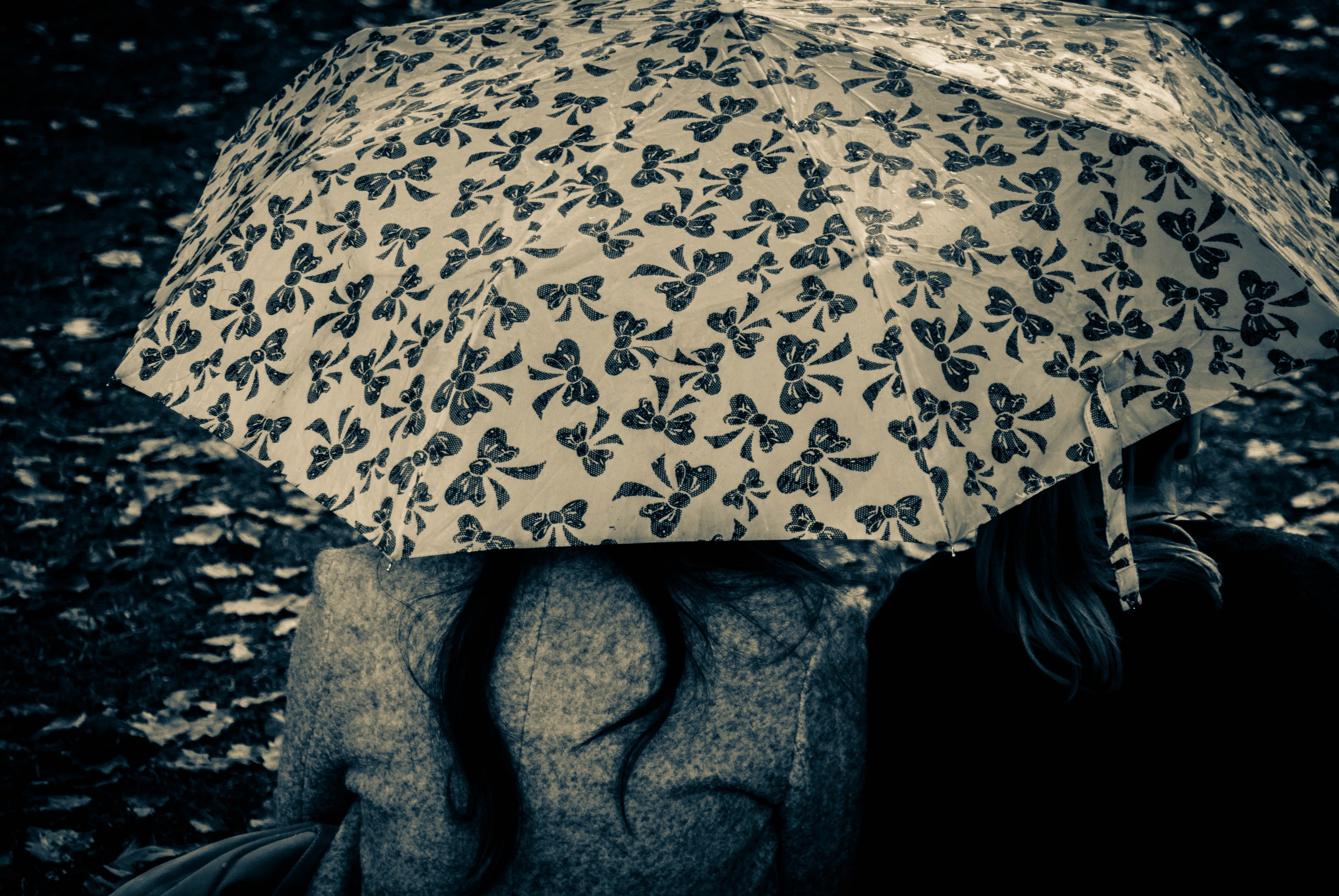 grayscale photo of person using umbrella with ribbon decors