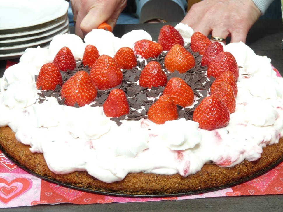 round cake topped with white icing and red strawberries preview