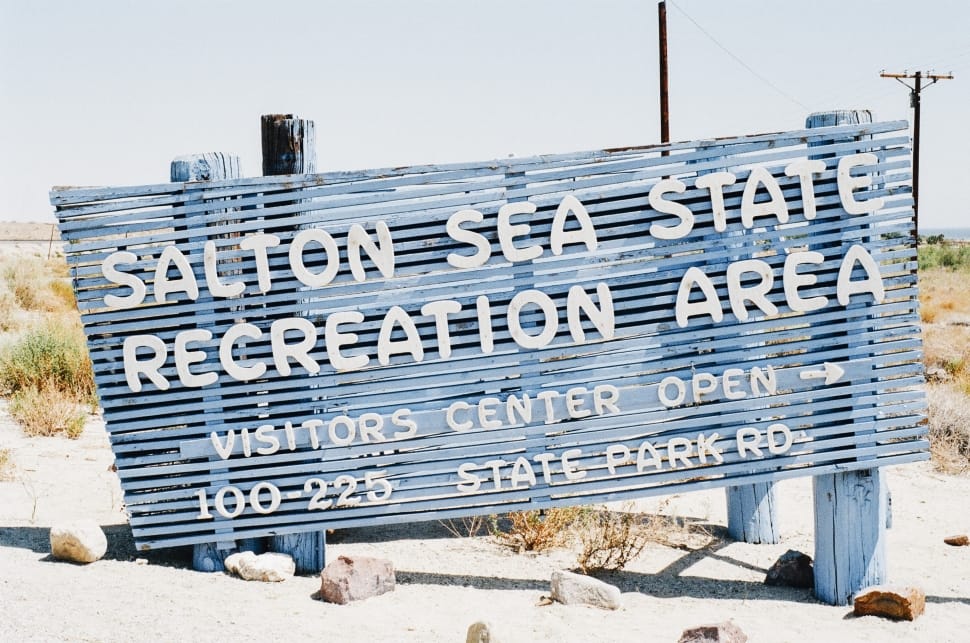 blue and white wooden salton sea state recreation are signage on white sand during day time preview