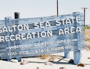 blue and white wooden salton sea state recreation are signage on white sand during day time thumbnail