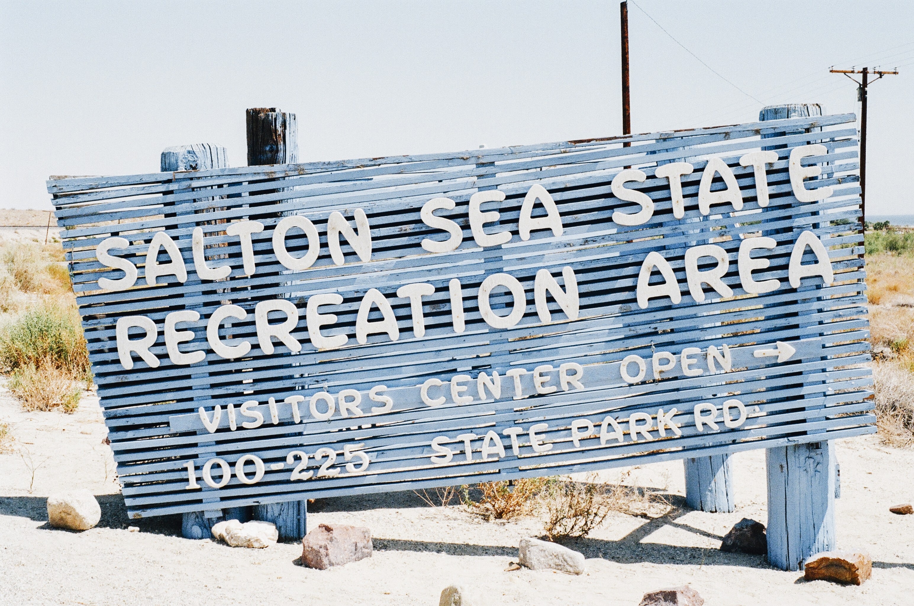 blue and white wooden salton sea state recreation are signage on white sand during day time