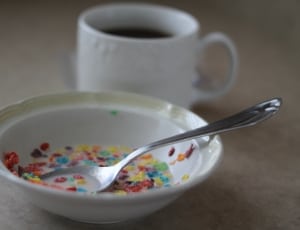 multi-colored ceramic bowl with stainless steel spoon and ceramic cup with black liquid thumbnail