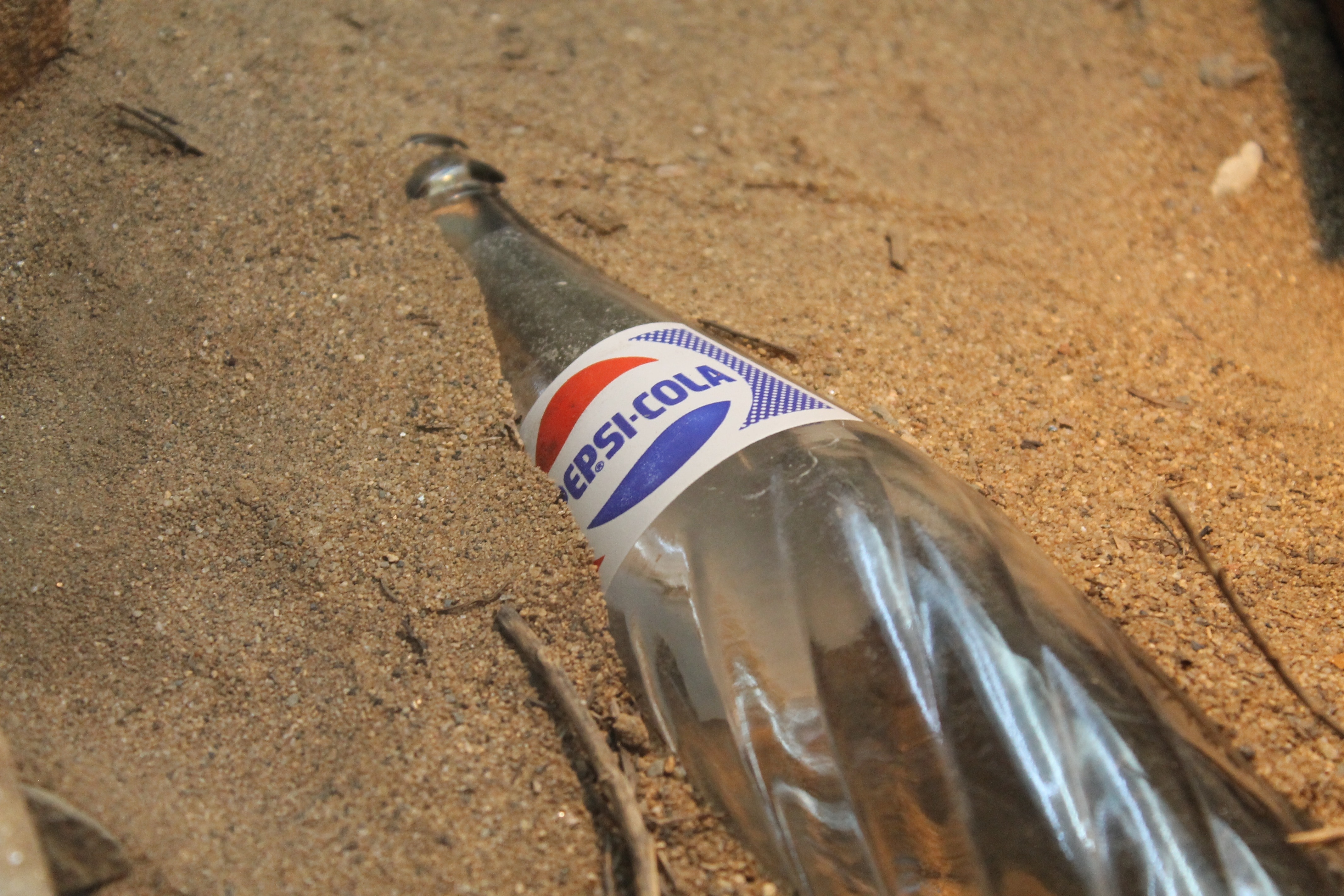 Pepsi-Cola bottle on sand