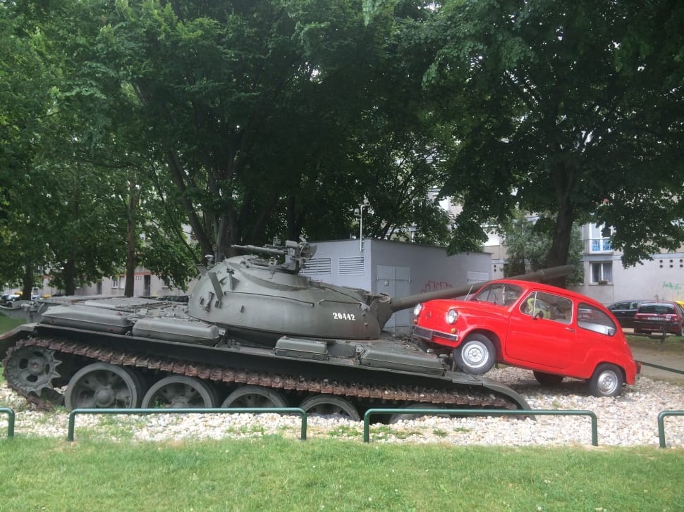 black battle tank beside red car preview