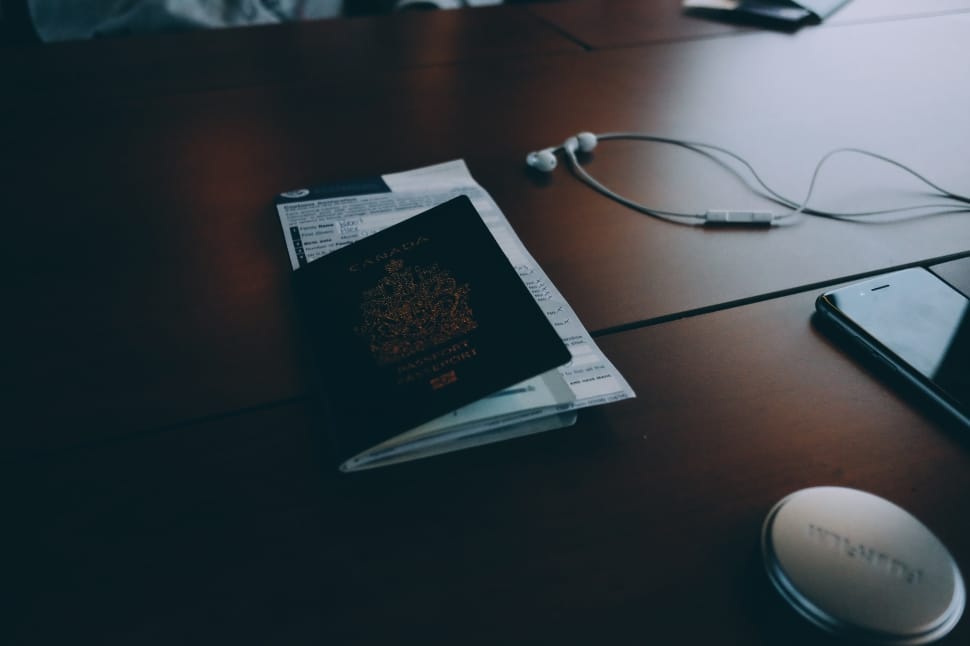 passport beside the white earphones on the brown wooden table preview