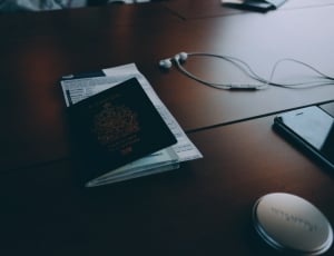 passport beside the white earphones on the brown wooden table thumbnail
