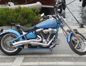 blue, black and gray chopper motorcycle parked near body of water thumbnail