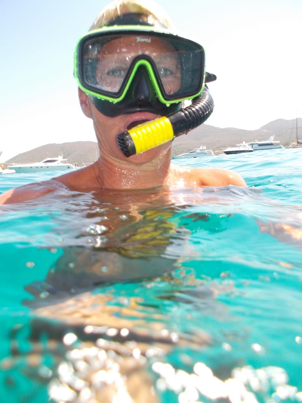 person with green and black swimming goggles on body of water preview