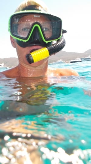 person with green and black swimming goggles on body of water thumbnail