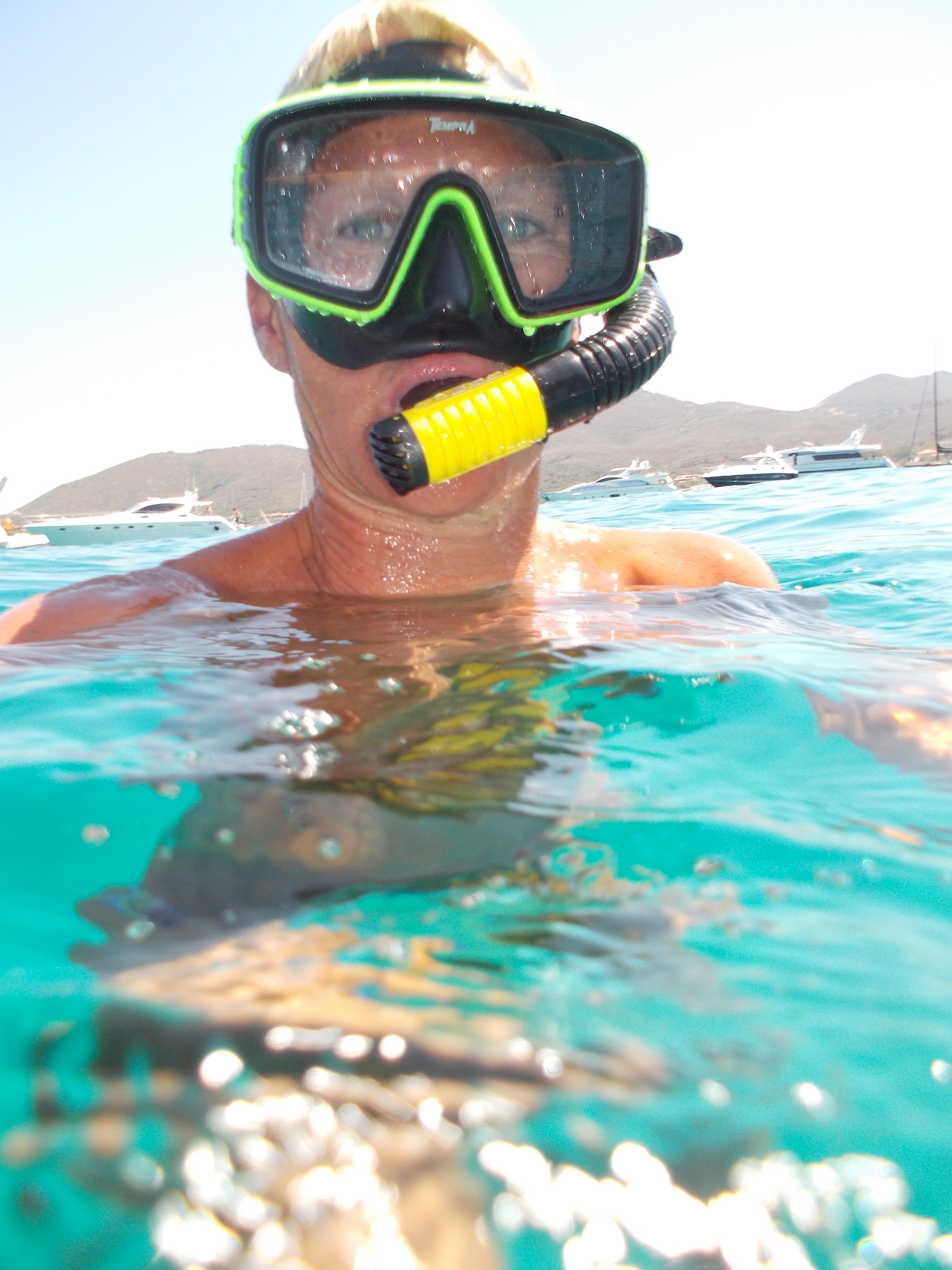 person with green and black swimming goggles on body of water