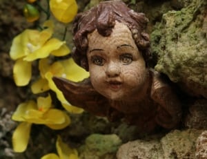 baby figurine and yellow petaled flower thumbnail