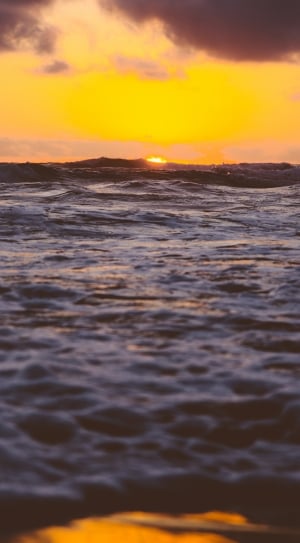 blue body of water under orange sky during sunset thumbnail