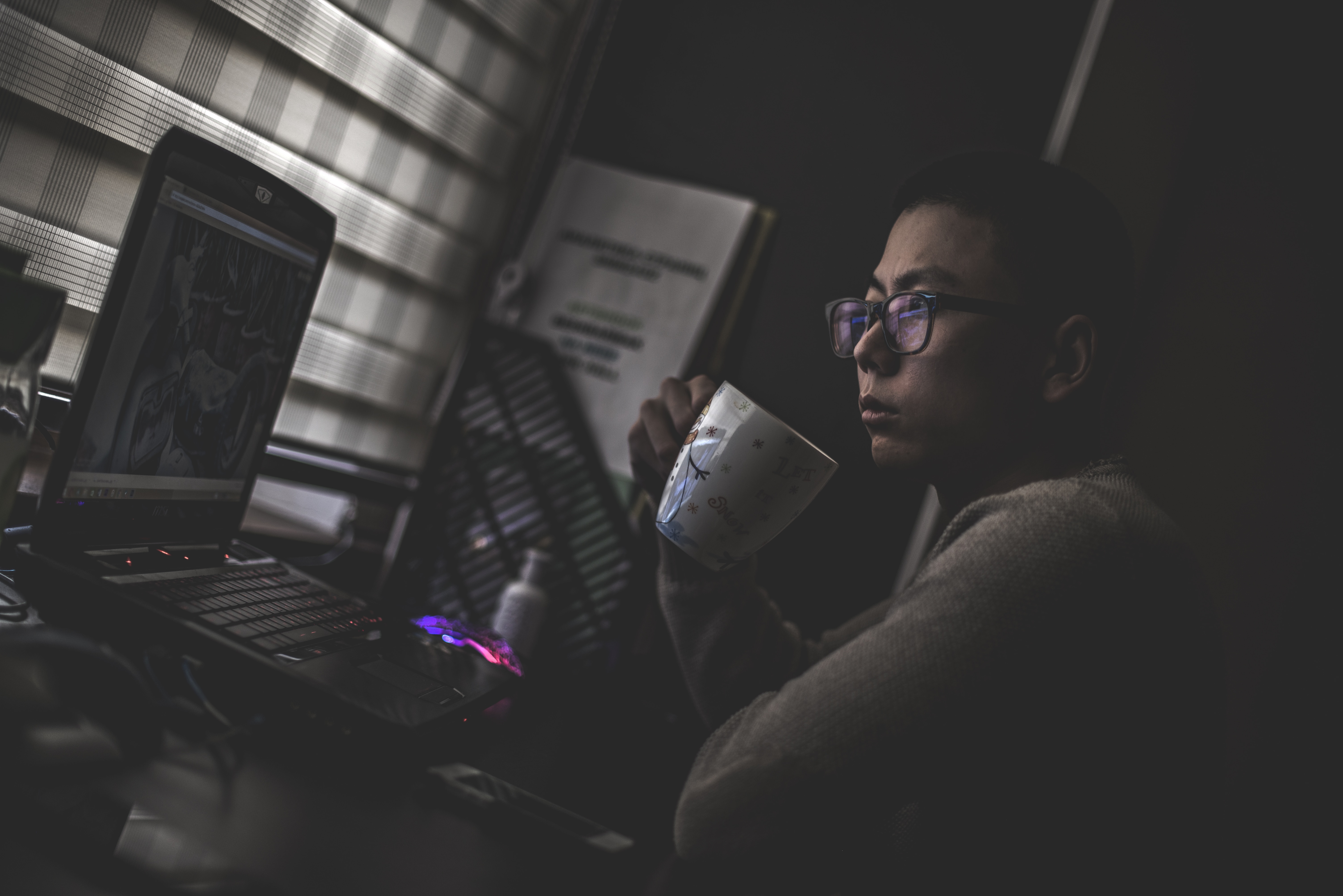 a woman is holding a mug watching movie in her laptop