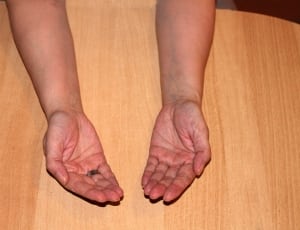 person laying both hands of brown wooden table thumbnail