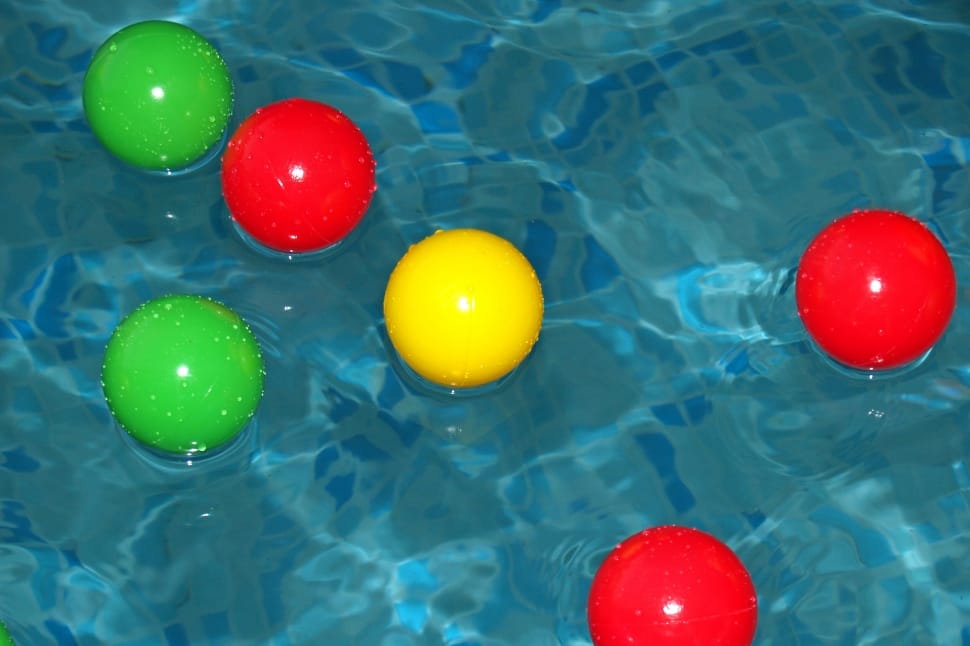 assorted rubber balls on body of water preview