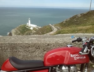 red royal enfield standard motorcycle and white lighthouse thumbnail