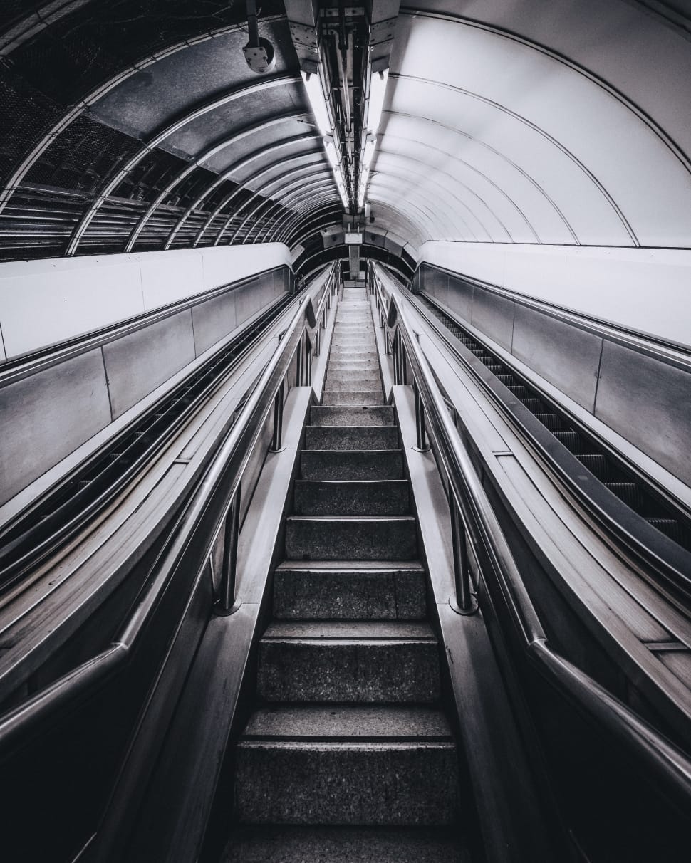 low angle greyscale photography of an escalator inside a tunnel preview