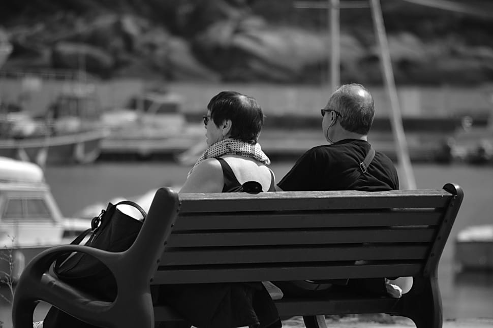grayscale photography of 2 person sitting on bench photo preview