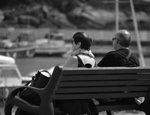 grayscale photography of 2 person sitting on bench photo thumbnail