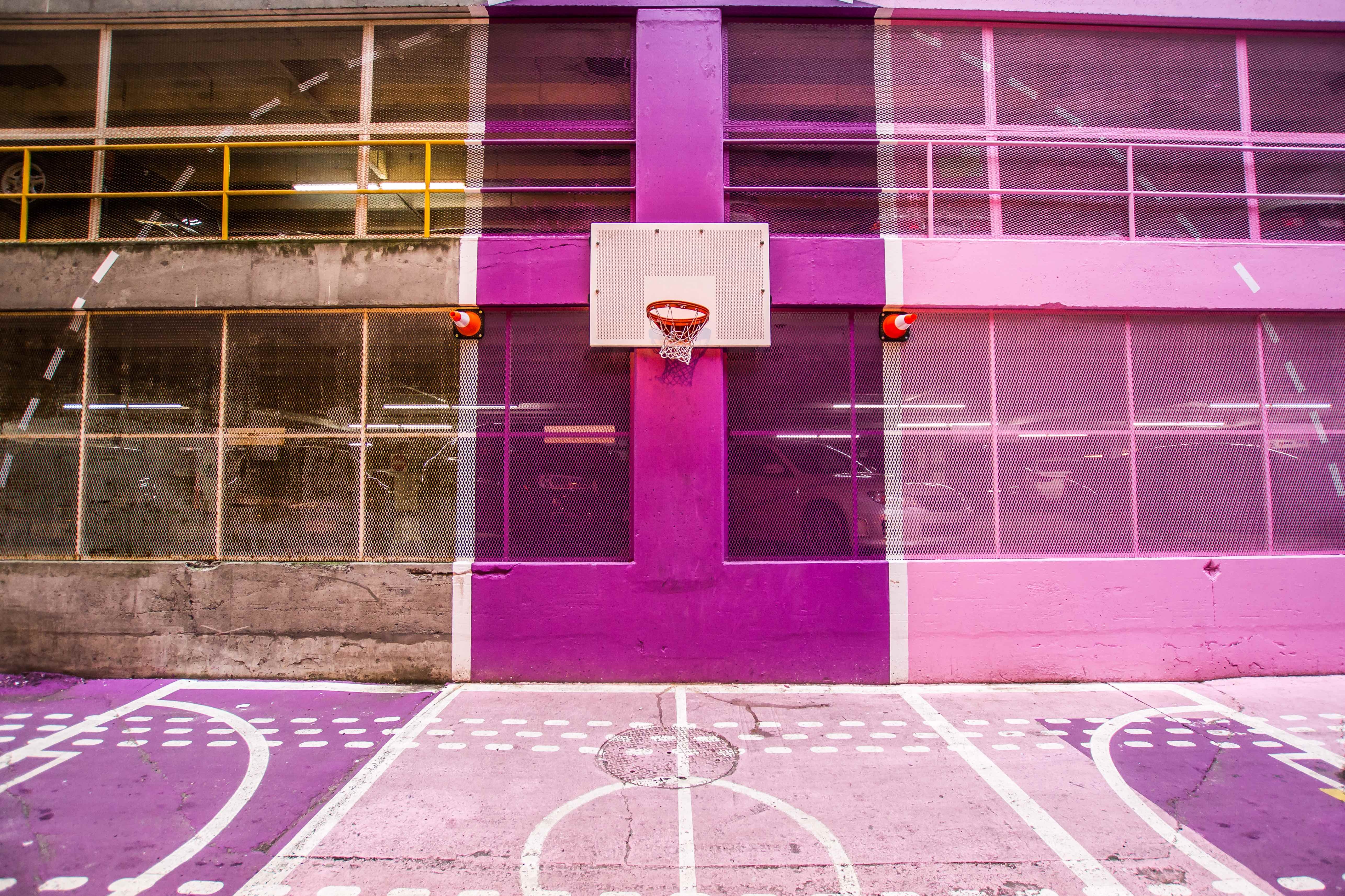 white and brown basketball board mounted in purple concrete high rise building