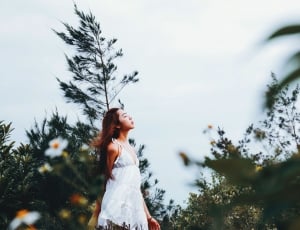 woman wearing white dress between trees during night time thumbnail