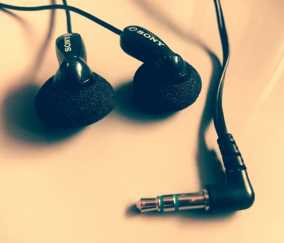 closeup photo of black Sony earphones on beige panel preview