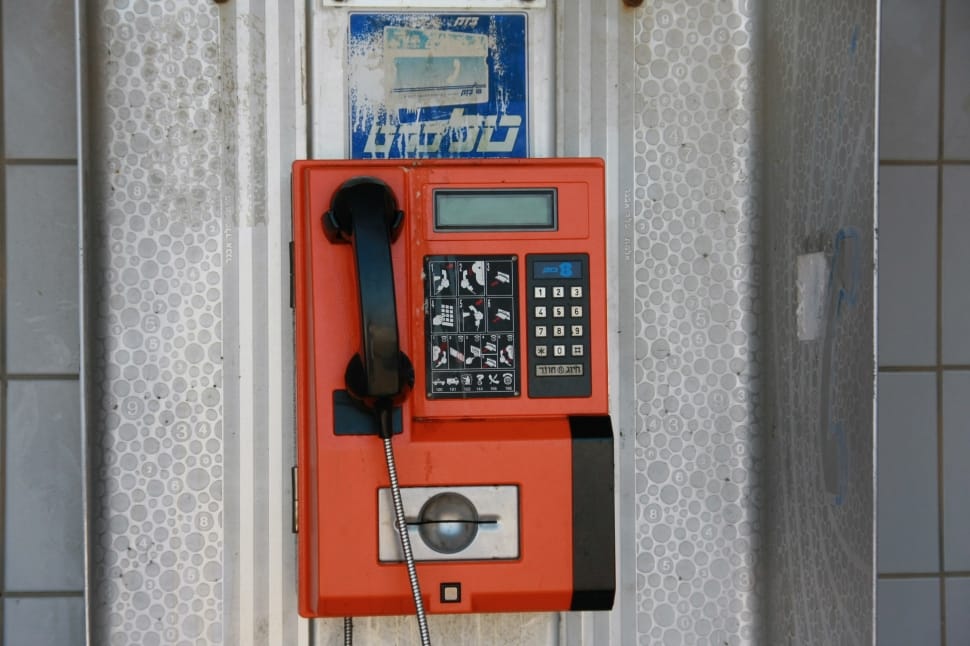 red and black coin operated telephone on wall during daytime preview