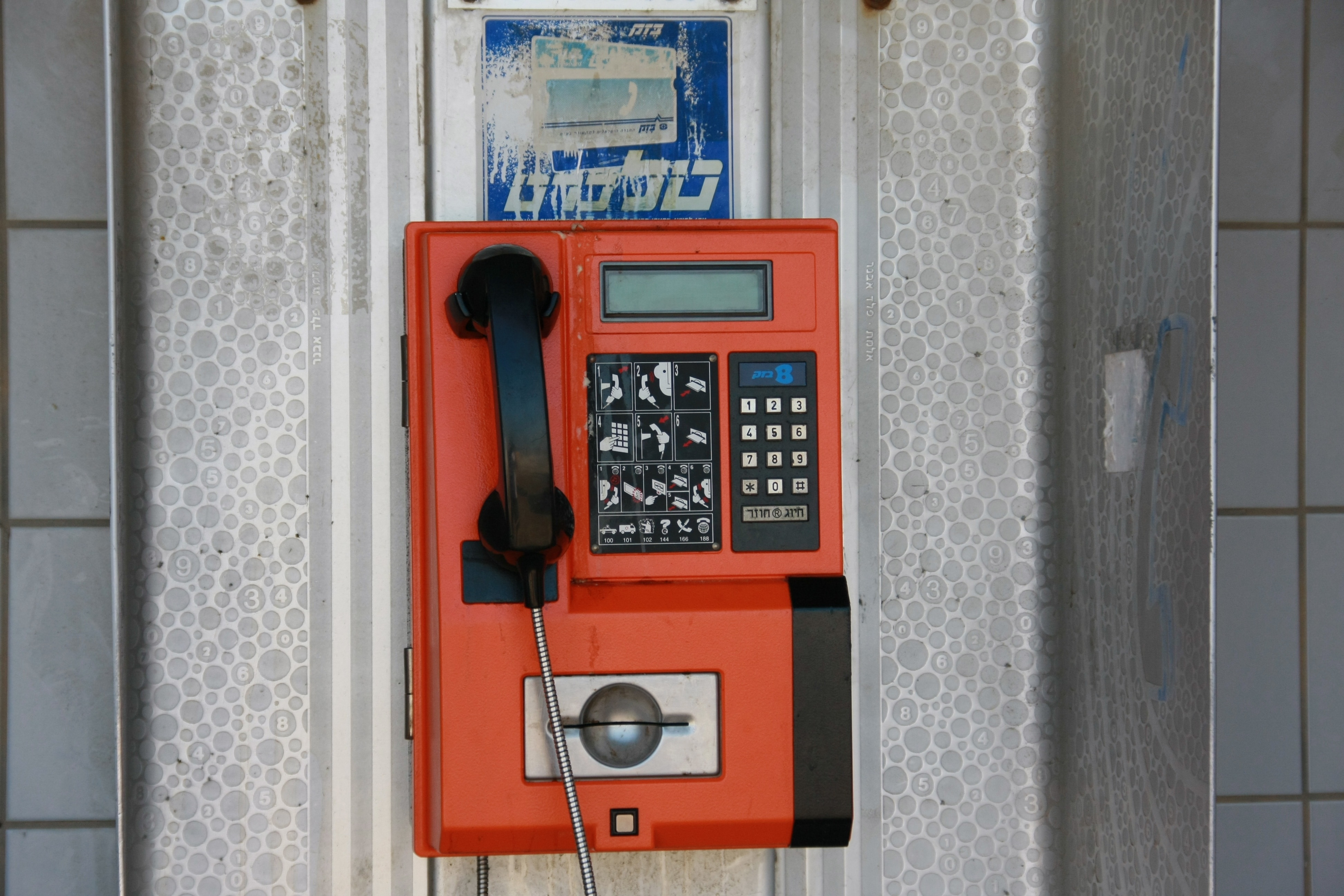 red and black coin operated telephone on wall during daytime