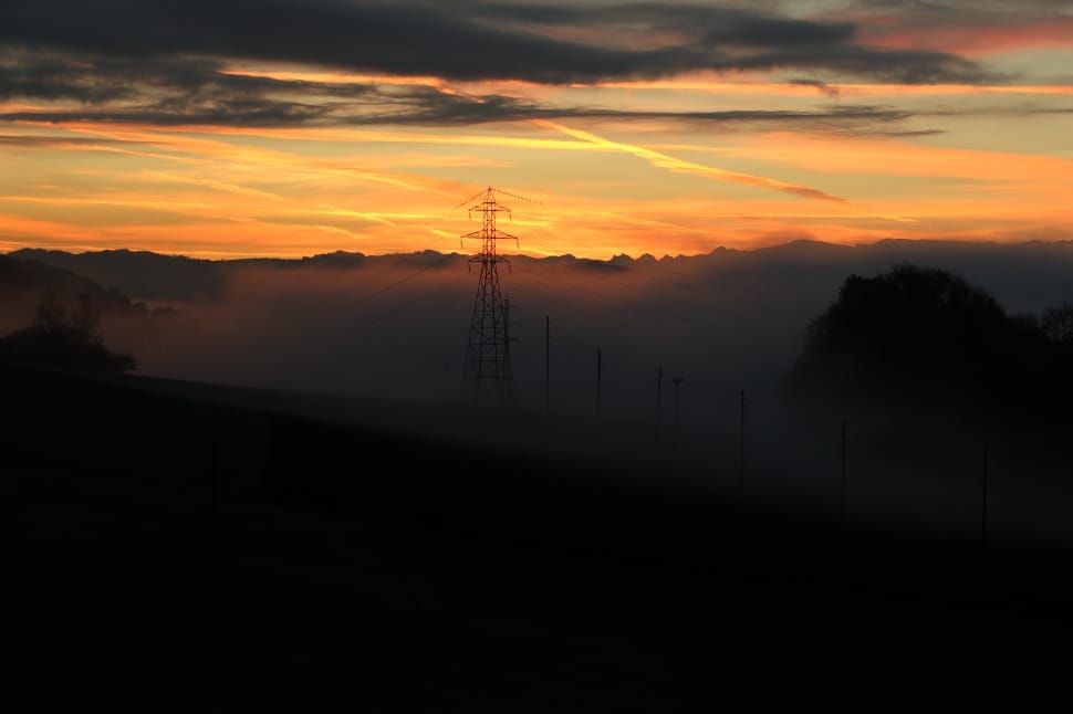 silhouette photography of electric post in high mountain during sunset preview