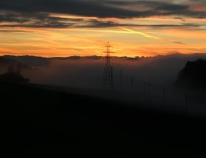 silhouette photography of electric post in high mountain during sunset thumbnail