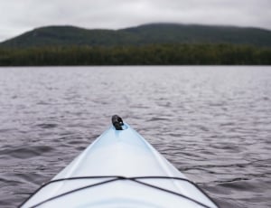white kayak on water far from mountains at daytime thumbnail