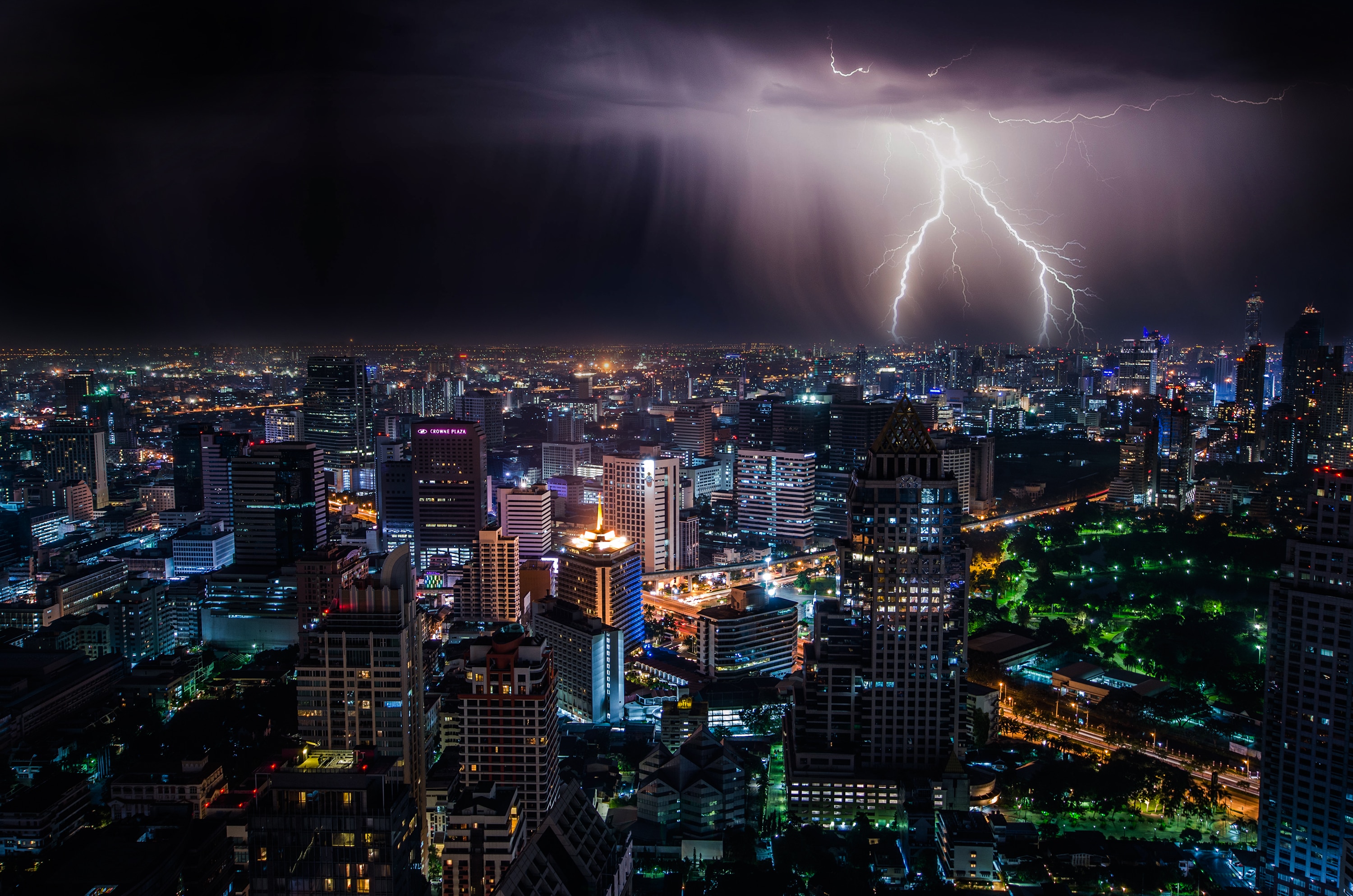 city with buildings under dark clouds with lightning