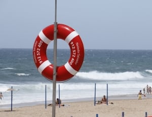 red and white Inflatable ring hanging on gray steel post on gray sand thumbnail