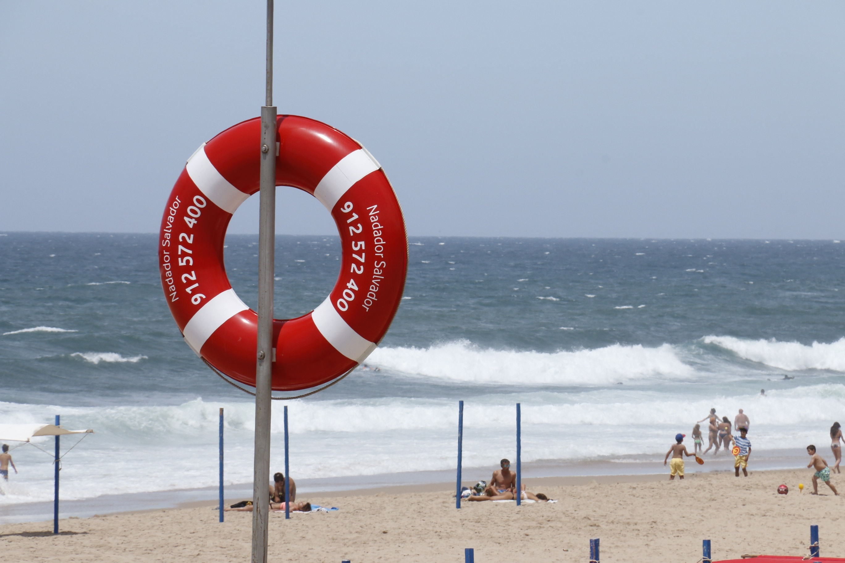 red and white Inflatable ring hanging on gray steel post on gray sand