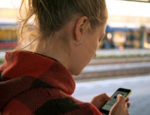 woman in red hoodie using yellow smartphone thumbnail