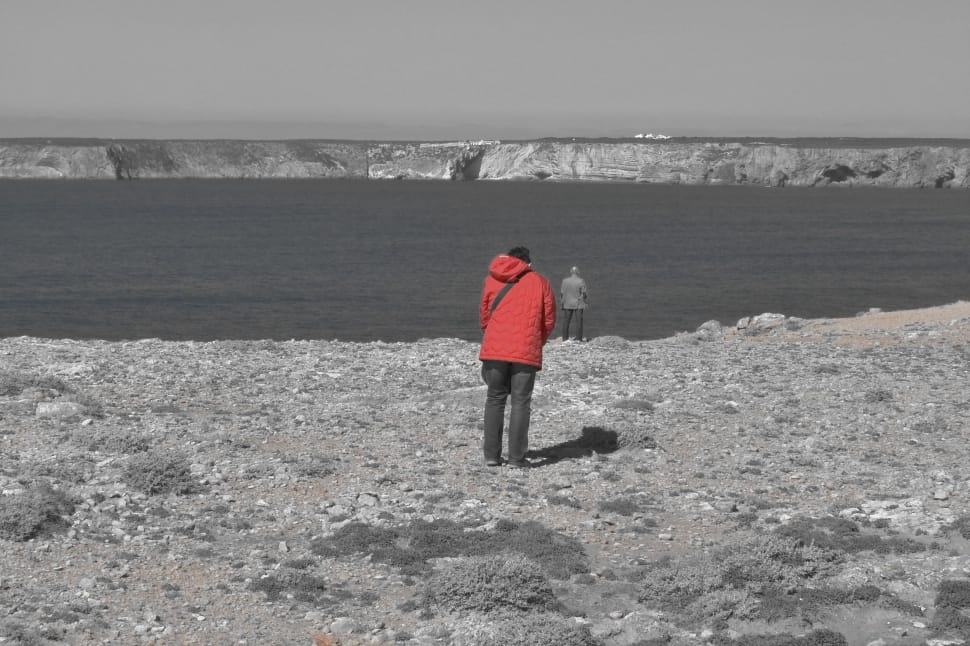 man in red jacket standing near the lake preview