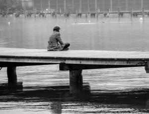 grayscale photography of woman sitting on wooden dock thumbnail