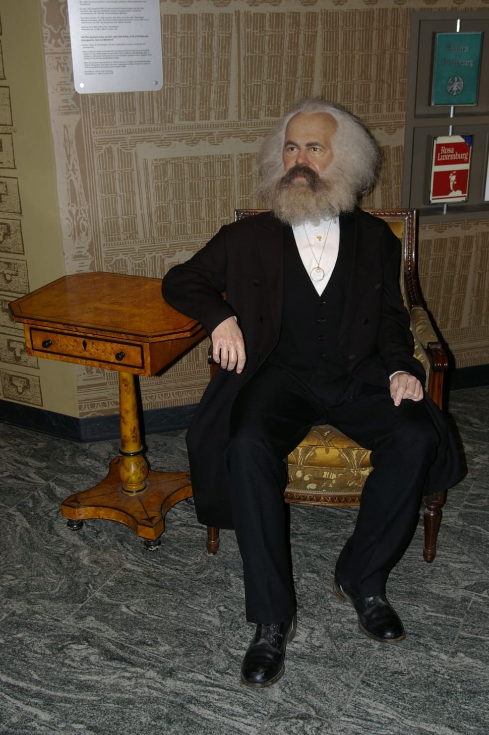 bearded man in black suit sitting on wooden armchair preview