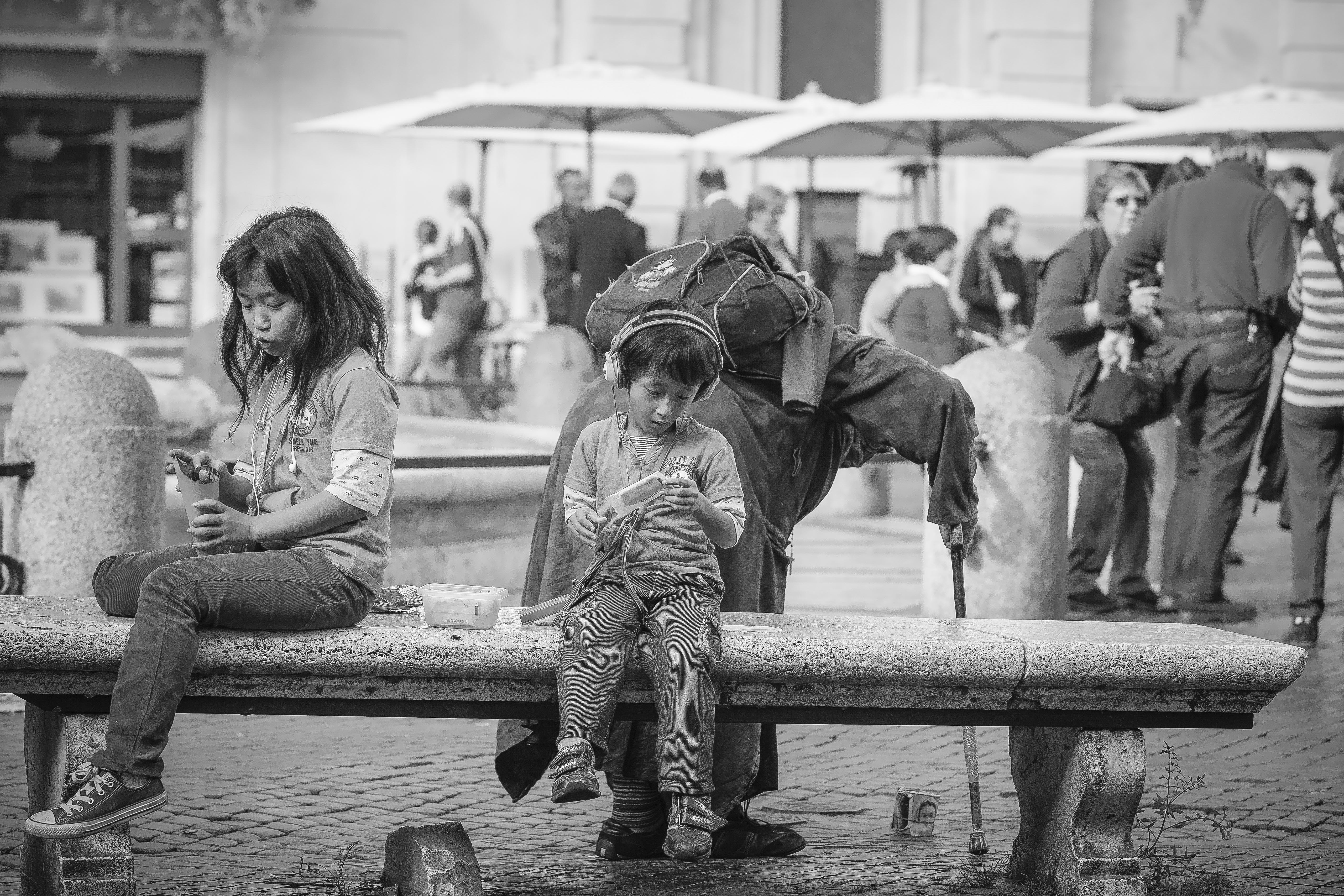 grayscale photo of boy and girl sitting on bench