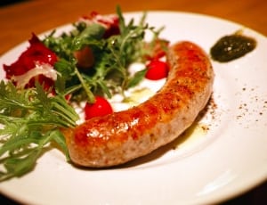brown sausage and veggies on white ceramic plate thumbnail