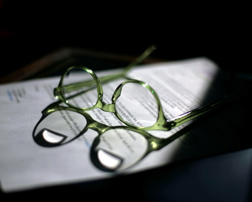 green frame eyeglasses on white printed paper preview