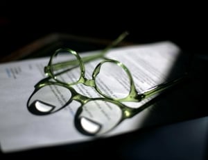 green frame eyeglasses on white printed paper thumbnail