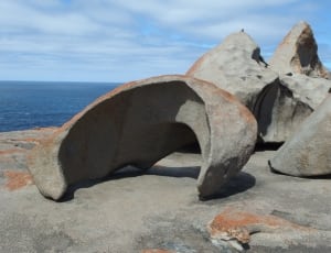 gray stone boulder near ocean thumbnail